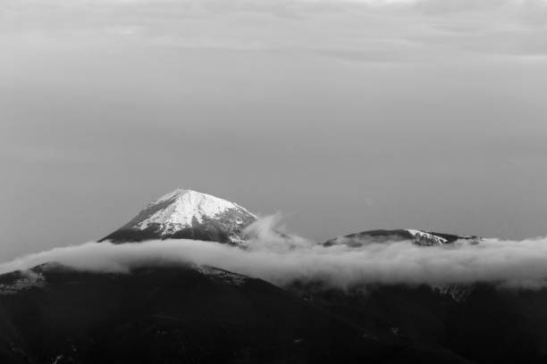 istock Mountain top covered by snow in the middle of clouds 1168115920
