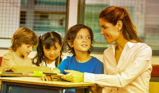 istock Back to school. Latin elementary school students. Smiling group of primary school students with teacher having fun with tablet 1168116710