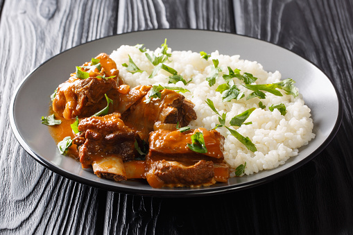 Slowly cooked short ribs in a spicy sauce with rice side dish close-up on a plate on the table. horizontal