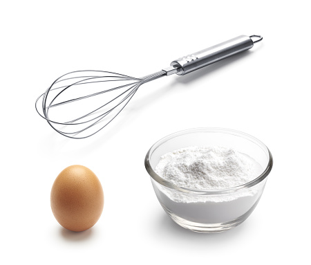Baking ingredients - balloon whisk, egg and flour isolated on white background