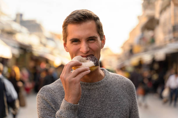 istock young man eating a donut in an alley 1168123447