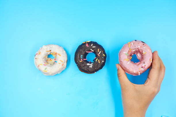 istock Female hand holding Doughnut on a blue background 1168126020