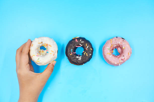 istock Female hand holding Doughnut on a blue background 1168126023