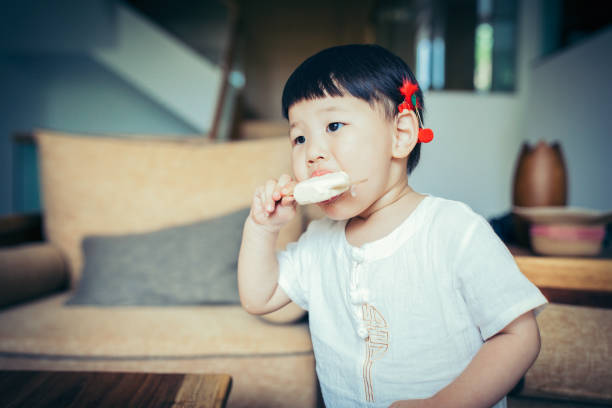 Portrait of Chinese little girl eating ice cream at home. Eating, Child, Food, Baby - Human Age, Baby Girls, Ice Cream, Shanghai asian little chinese girls eating ice cream stock pictures, royalty-free photos & images