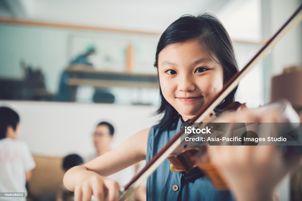 Asian Little Girl playing violin at home. Child, Girls, Asian and Indian Ethnicities, Violin, 10-111 Years, Family Music Stock Photo