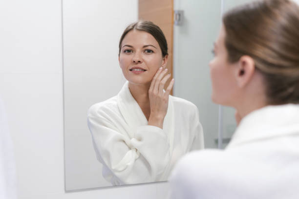 istock Woman in bathrobe looking in mirror at bathroom 1168144230