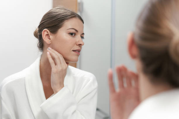 istock Woman in bathrobe looking in mirror at bathroom 1168144665