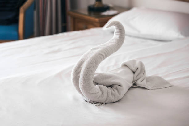 istock Beautiful swan from white bath towel decorate on bed corner and soft sunlight in background, nice greeting from Hotel. 1168145795