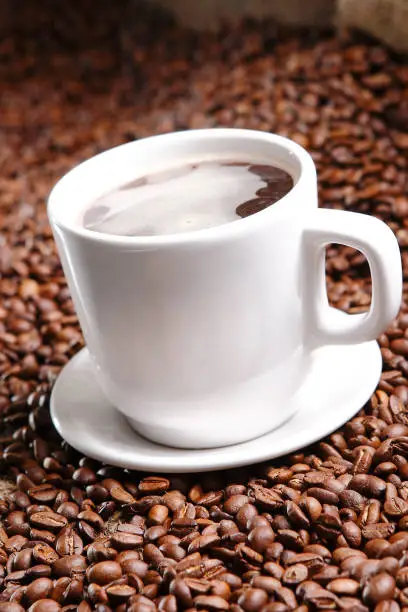 Photo of Coffee with grains and sweet bread. Coffee is a brewed drink prepared from roasted coffee beans, the seeds of berries from certain Coffea species.