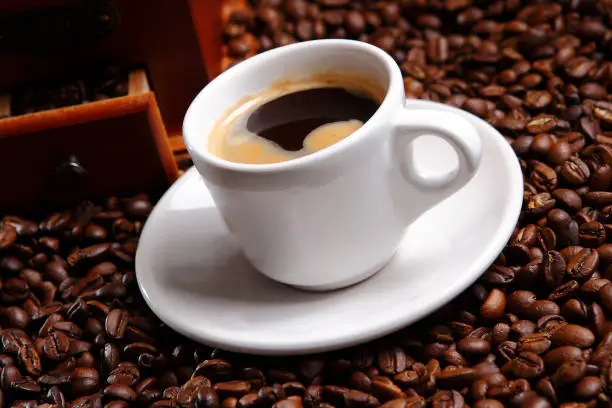 Photo of Coffee with grains and sweet bread. Coffee is a brewed drink prepared from roasted coffee beans, the seeds of berries from certain Coffea species.