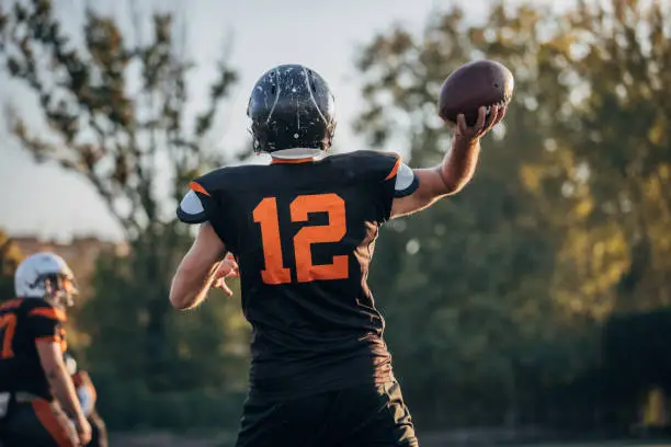 Two men, American football players on rough training outdoors.