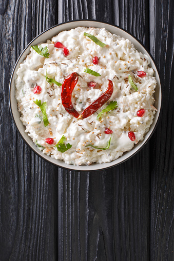 Comforting Curd Rice is a popular dish from South India with yogurt and then tempered with spices closeup in a plate on the table. Vertical top view from above