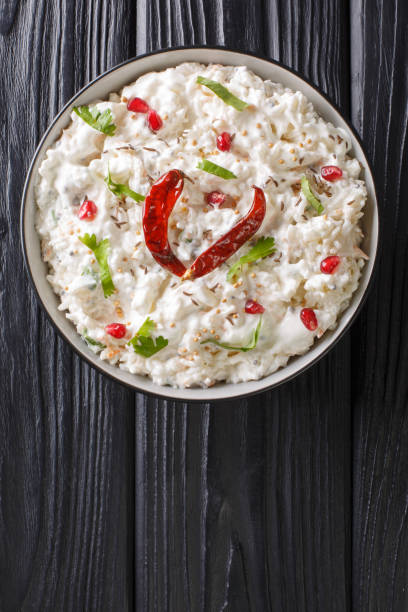 Comforting Curd Rice is a popular dish from South India with yogurt and then tempered with spices closeup in a plate. Vertical top view stock photo