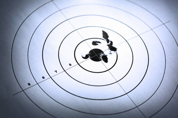 istock Spot lit target with closely-grouped holes around bulls eye 1168155406