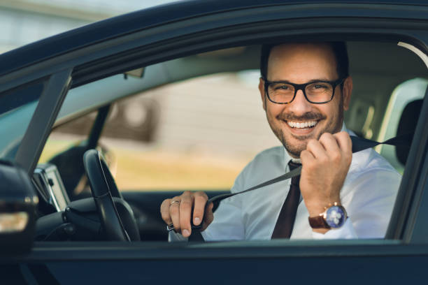 Businessman  fastening his seat belt Happy businessman fastening his seat belt in a car car ownership photos stock pictures, royalty-free photos & images
