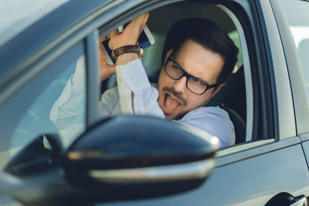 istock Frightened businessman holding a cell phone while driving a car 1168162273