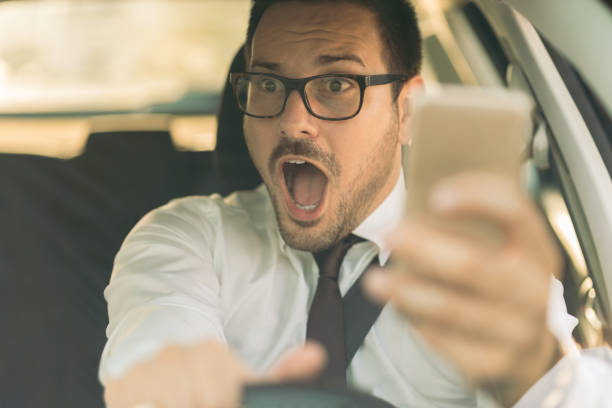 istock Frightened businessman holding a cell phone while driving a car 1168162279