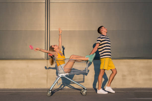 istock Joyless boyfriend pulling his girlfriend who is having fun in a shopping cart 1168162467