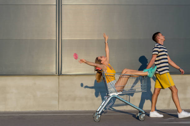 istock Joyless boyfriend pulling his girlfriend who is having fun in a shopping cart 1168163062