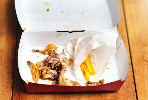 Looking down into a  box with the remains of of a takeout crispy chicken and French fries meal.