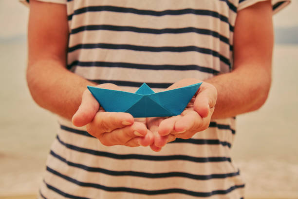 istock Man holding paper boat on tropical beach. 1168171885