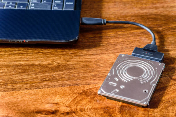 istock hdd 2.5 internal hard drive disk connected to laptop via sata usb cable on wooden table closeup view 1168175461