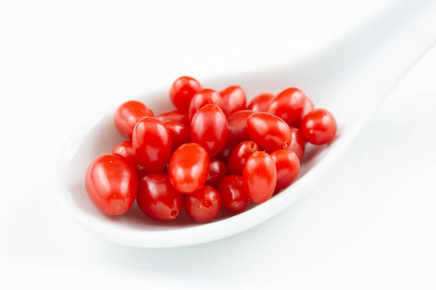 fresh goji berries in a small white porcelain spoon isolated on white copy space closeup
