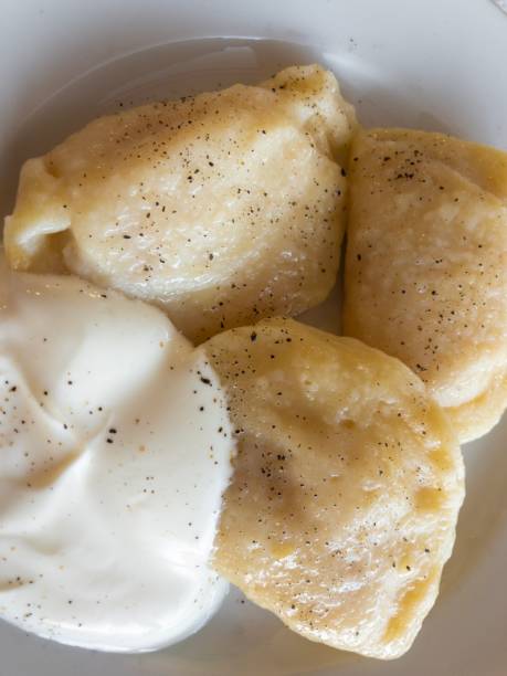 istock Plate with three Ukrainian vareniky stuffed with mashed potato, flavored with black pepper and served with sour cream 1168178916