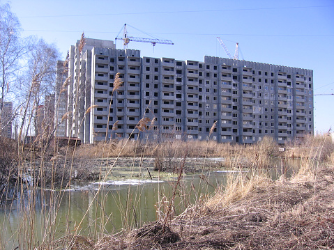 building under construction depressive panel apartment building near the overgrown swampy area near the swamp in the grass in the wasteland on the outskirts of the city