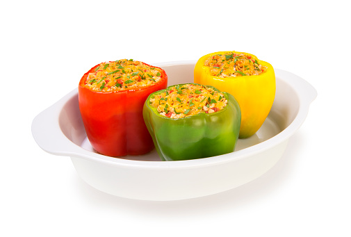 colorful baked with cheese stuffed peppers with minced turkey and vegetables in a white casserole baking isolated on a white background