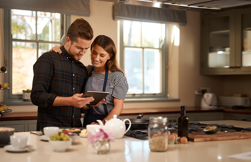 Shot of an affectionate couple using a digital tablet while cooking in the kitchen