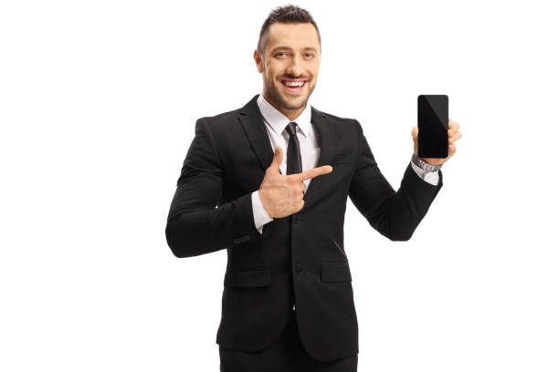istock Cheerful young man in a suit holding a mobile phone and pointing at it 1168186418