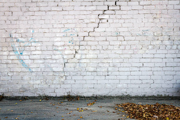 Old cracked white brick wall Old cracked white brick wall and ground graffiti brick wall dirty wall stock pictures, royalty-free photos & images