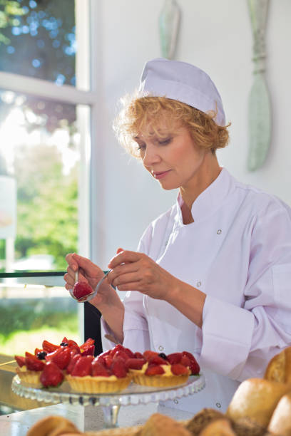 Mature chef arranging fresh strawberry tarts in restaurant