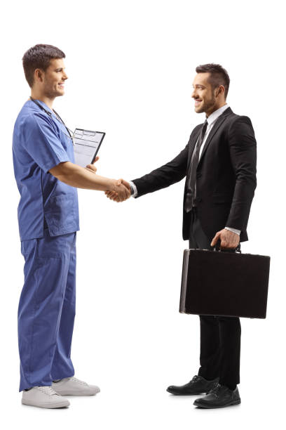 doutor masculino novo em um uniforme azul que agita as mãos com um homem de negócios - isolated smiling business person handshake - fotografias e filmes do acervo