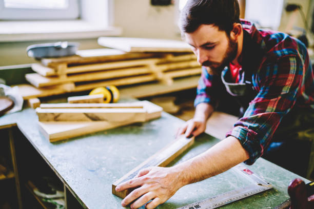 istock Serious bearded male maker checking measures of wooden bricks with ruler planning construction and engineering, skilled man student of carpentry courses checking details for construction in workshop 1168188530