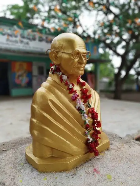 A gold colored statue of Gandhi inside a school premise