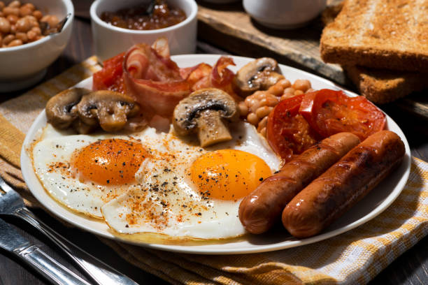 istock Fried eggs with bacon, sausages and vegetables 1168191074