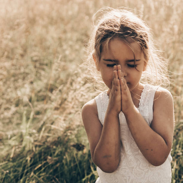 Little girl closed her eyes, praying outdoors, Hands folded in prayer concept for faith, spirituality and religion. Peace, hope, dreams concept. Little girl closed her eyes, praying outdoors, Hands folded in prayer concept for faith, spirituality and religion. Peace, hope, dreams concept. religion sunbeam one person children only stock pictures, royalty-free photos & images