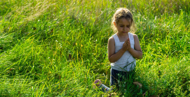 Little girl closed her eyes, praying outdoors, Hands folded in prayer concept for faith, spirituality and religion. Peace, hope, dreams concept. Little girl closed her eyes, praying outdoors, Hands folded in prayer concept for faith, spirituality and religion. Peace, hope, dreams concept. religion sunbeam one person children only stock pictures, royalty-free photos & images