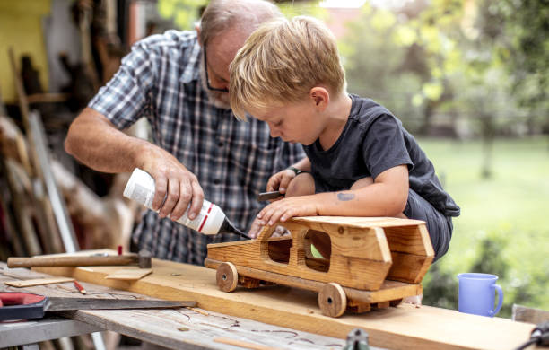 großvater und enkel machen ein auto aus holz - carpenter carpentry craft skill stock-fotos und bilder