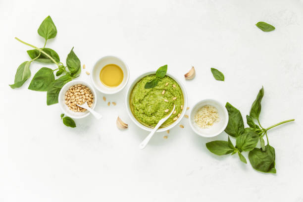 Freshly cooked italian pesto in a bowl and culinary ingredients, overhead view
