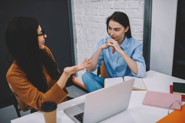 istock Cheerful girl telling her friend funny story while learning in campus with technology together, prosperous females colleagues having conversation about working tasks discussing ideas smiling 1168197028