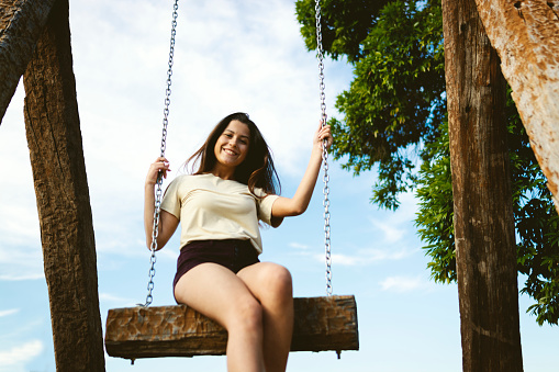 Teenage girl swinging and having fun in a public park