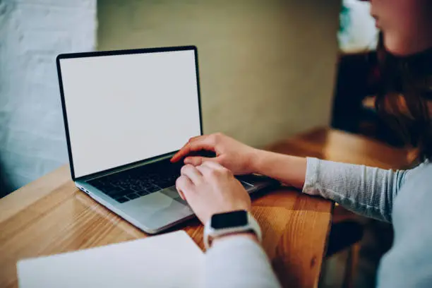 Photo of Cropped image of female typing on laptop computer creating publication for blog content . woman working on modern netbook connected to wireless internet in coworking office installing application