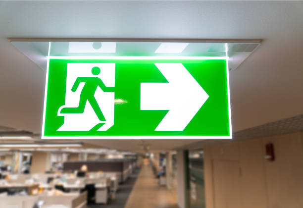 istock Green fire escape sign hang on the ceiling in the office. 1168205045