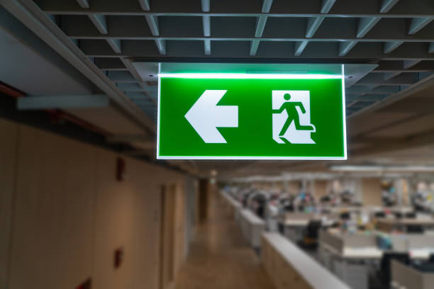 istock Green fire escape sign hang on the ceiling in the office. 1168205046