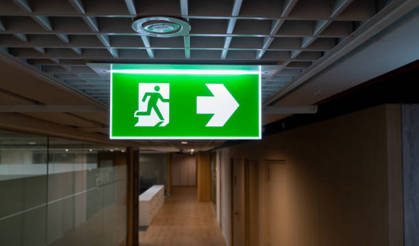 istock Green fire escape sign hang on the ceiling in the office. 1168205064