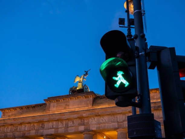 two icons of Berlin two icons of Berlin; Branderburger tor and the Ampelmann.  Typical and famous pedestrian traffic light of Berlin with walking green man "Ampelmannchen".  Pedestrian light is made by German technology company Siemens (see bottom left of light)." ampelmännchen photos stock pictures, royalty-free photos & images