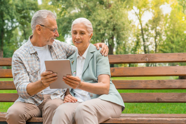 istock Happy retired couple sitting at park bench and using digital tablet 1168208116